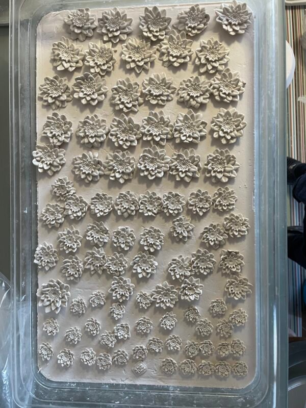 Pressed clay flowers ready for application.